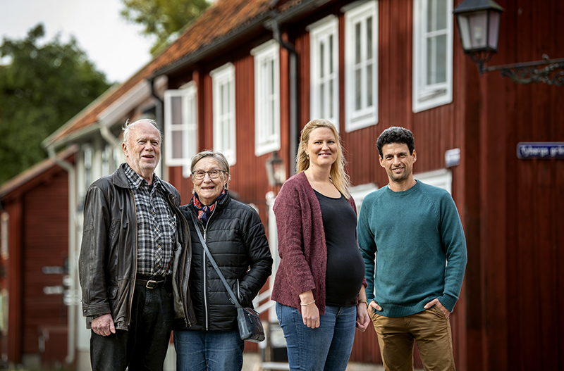 Fyra personer framför ett rött hus