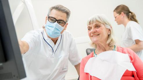 Tandläkare och patient vid dator