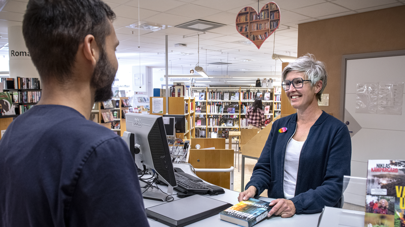 Besökare lånar bok vid utlåningsdisken i patientbiblioteket.