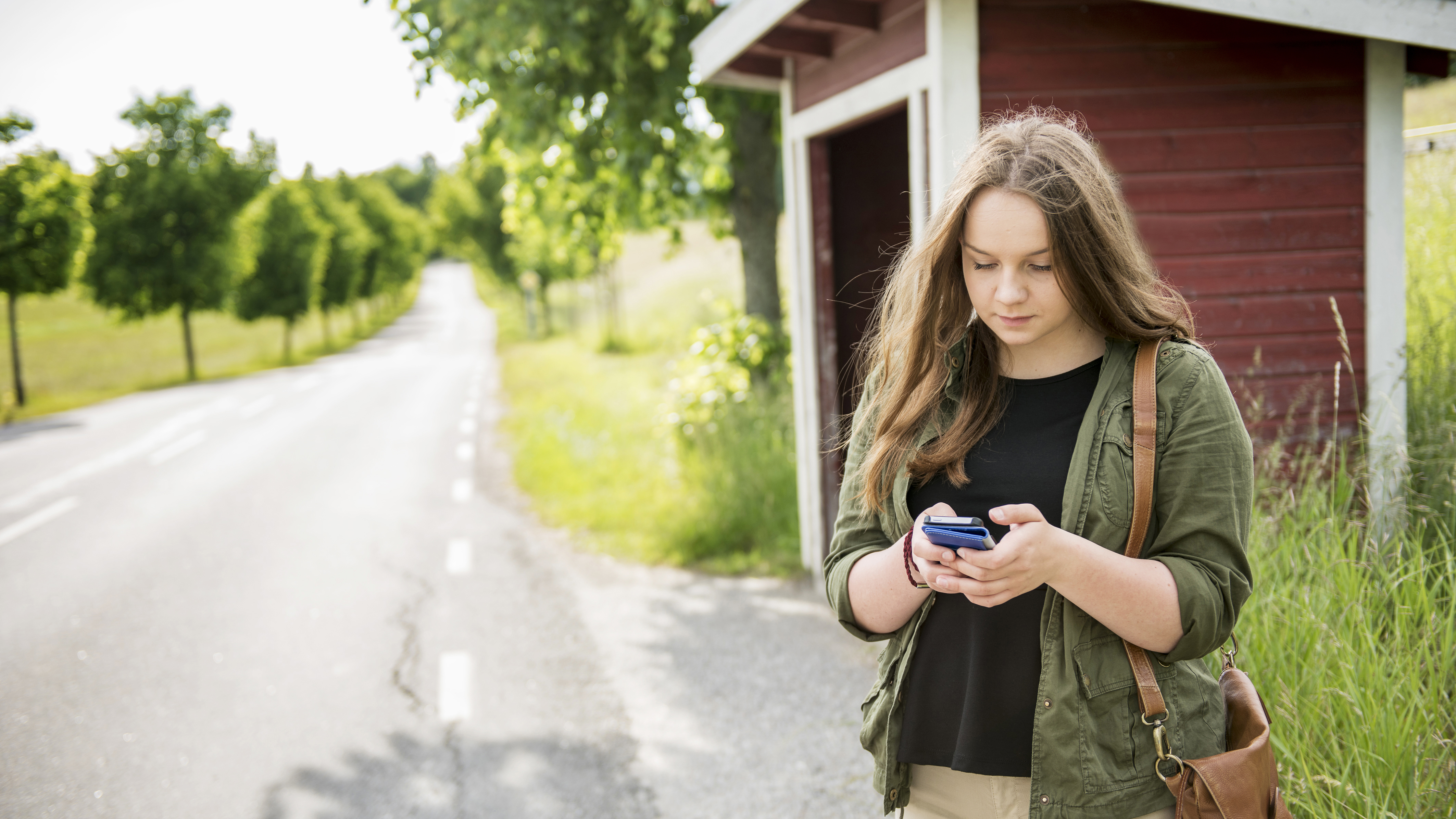 Ung tjej står utomhus och chattar med 1177 direkt 