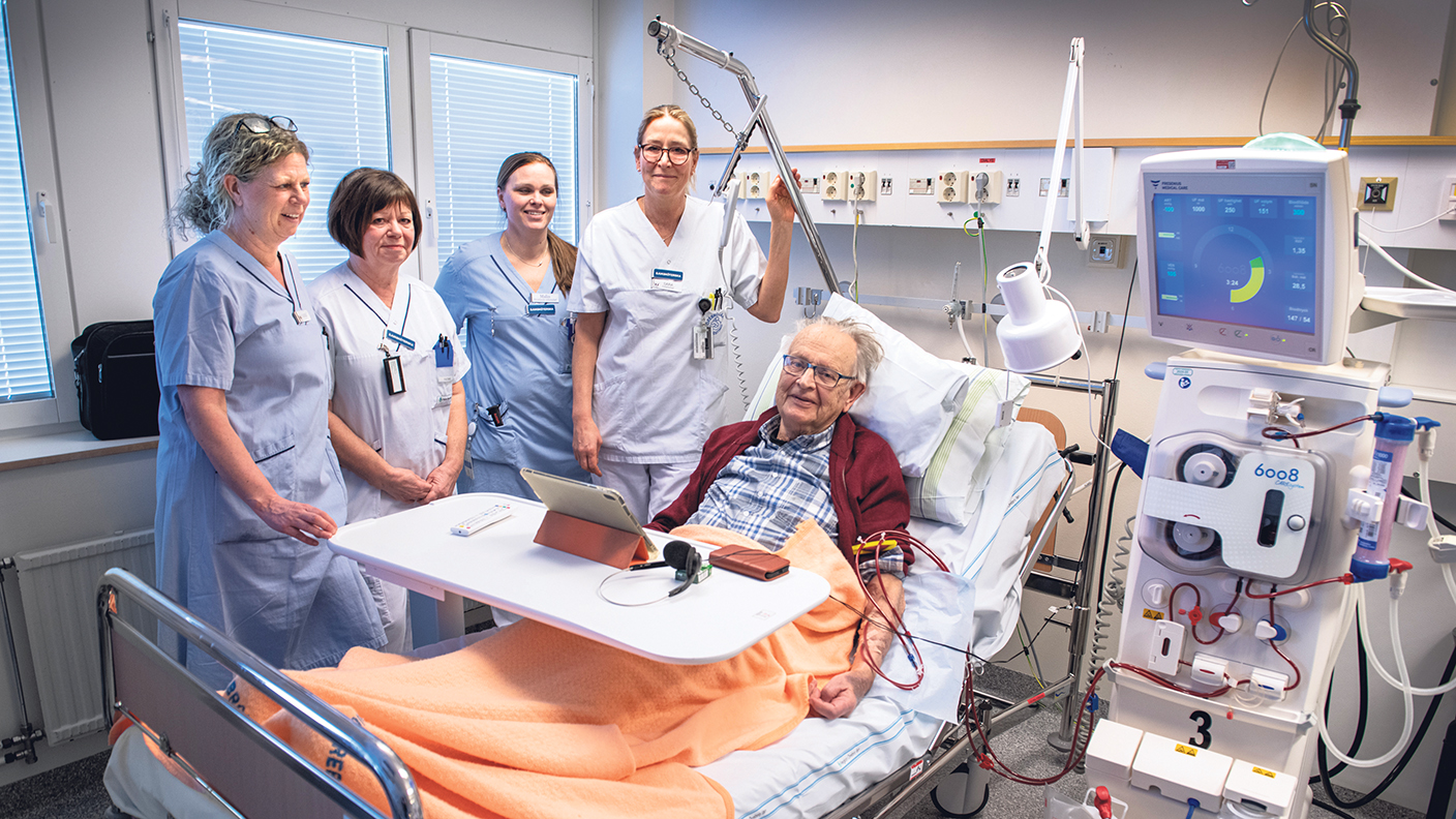 Patient i en säng med vårdpersonal runt omkring sig.