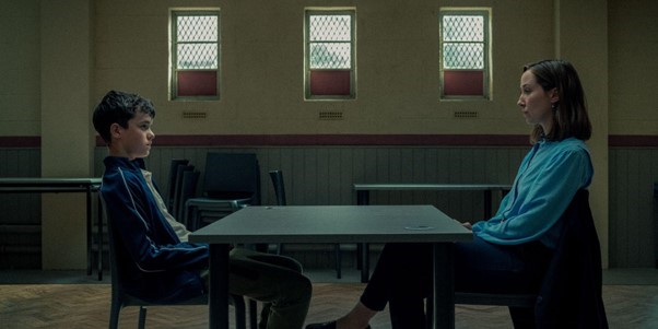 Pojke och kvinna sitter mittemot varandra vid ett bord